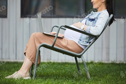 Preview: Pregnant woman working online on laptop