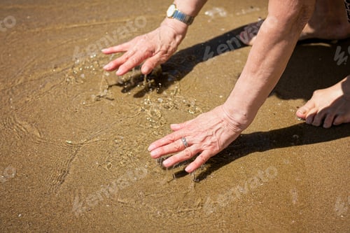 Preview: Elderly attractive woman touching the water on the seashore