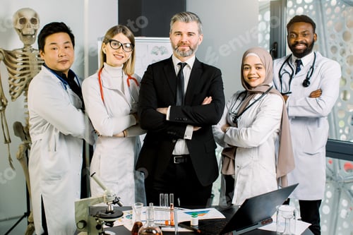 Preview: Mixed-race group of young doctors, lab workers, scientists, with male mature man supervisor, working