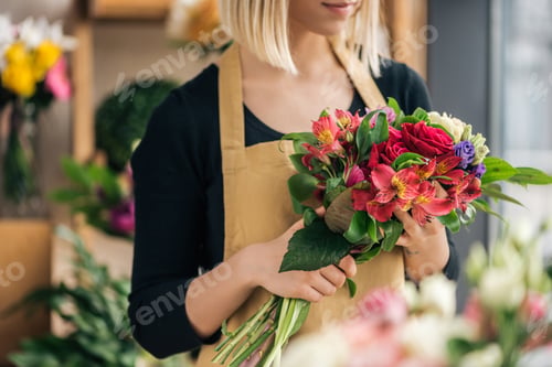 Preview: Cropped view of florist in apron holding bouquet in flower shop