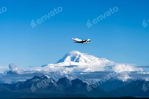 Preview: Plane flying over the mountains of Denali National Park against a blue sky