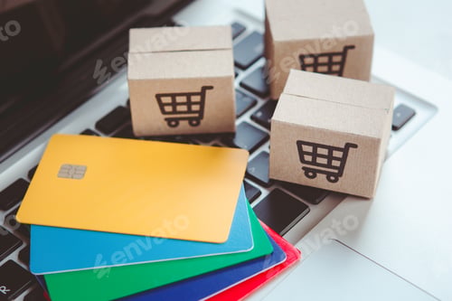 Preview: Shopping online. Credit card and cardboard box with a shopping cart logo on laptop keyboard.