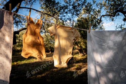 Preview: Baby clothes on clothesline drying in garden. Newborn childhood concept