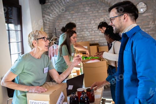 Preview: Group of volunteers working in community charity donation center.