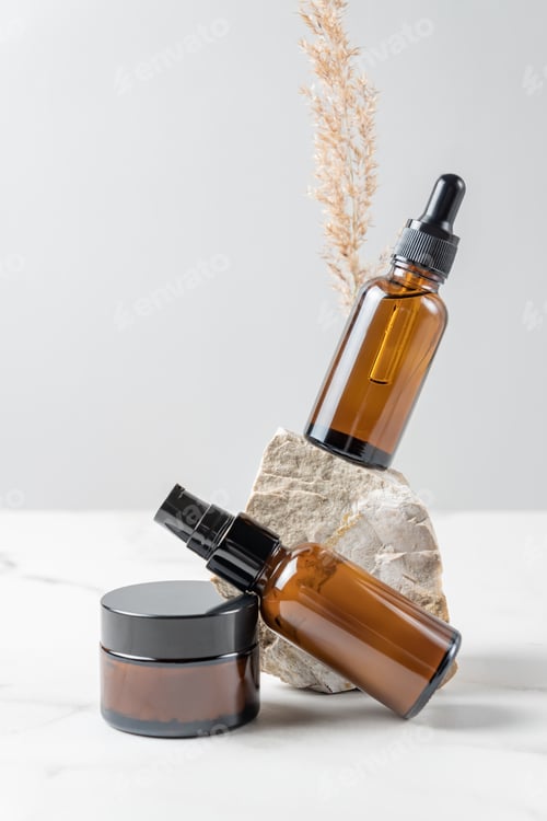 Preview: blank cosmetic bottles with cream, moisturizer or other cosmetic product, stones, dried plant flower