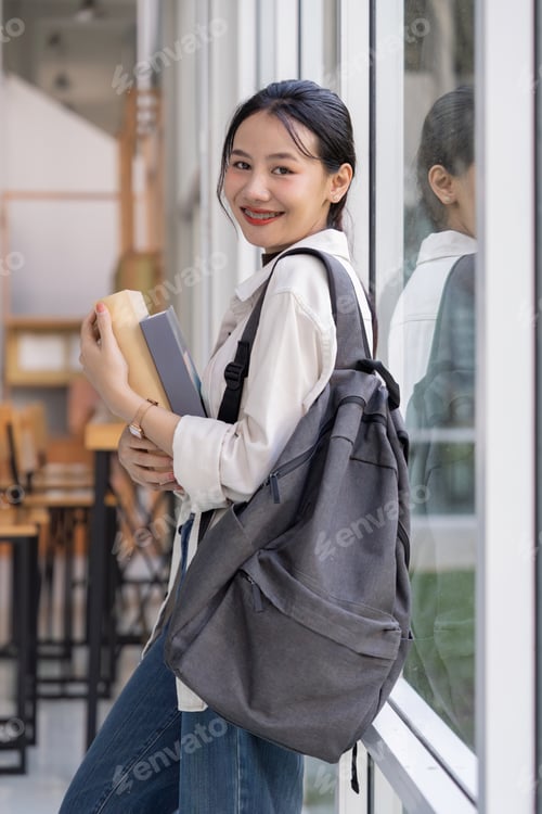 Preview: Beautiful young woman asian with backpack and book. College student carrying lots of books in