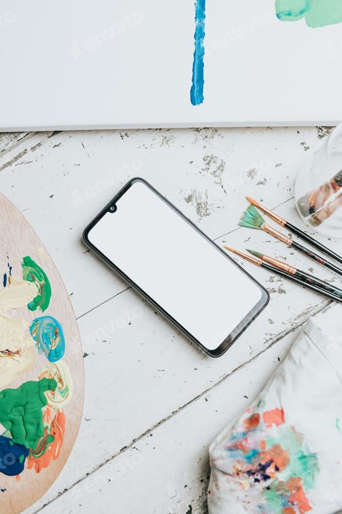 Preview: Mock up image of a mobile phone over a white table with a painting palette and painting