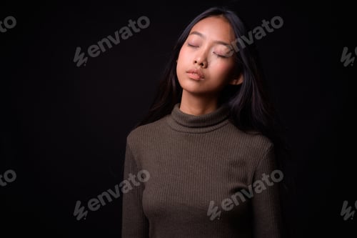 Preview: Young beautiful Asian woman against black background