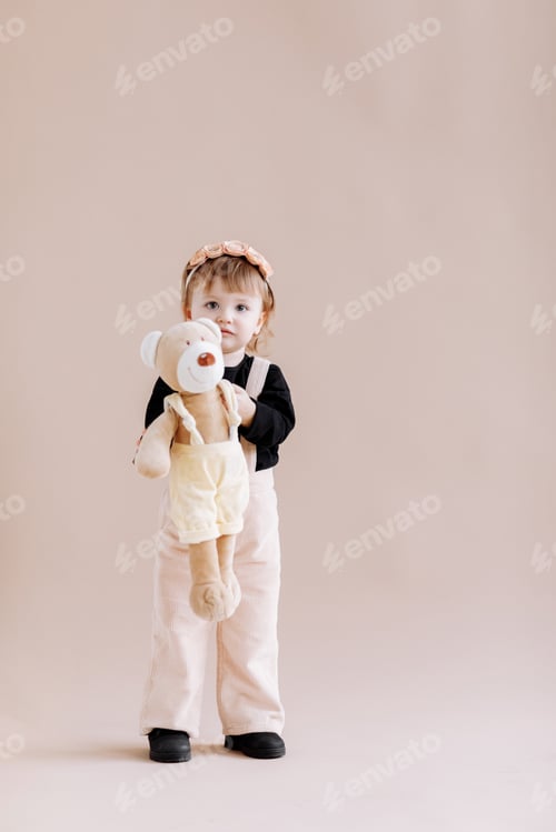 Preview: My favorite toy. Cute little 2 years old girl hugging her teddy bear and smiling, decorated beige