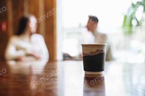Preview: Two People Engage in Conversation Behind Coffee Cup on Wooden Table
