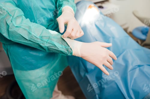 Preview: Person in scrubs puts on surgical gloves