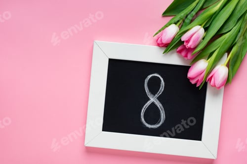 Preview: Top view of chalkboard with 8 number near tulips on pink background