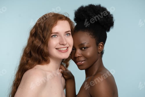 Preview: Two Diverse Women Smiling and Embracing on Blue Background