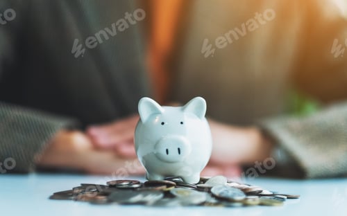 Preview: Closeup image of a woman and piggy bank on pile of coins on the table for saving money concept