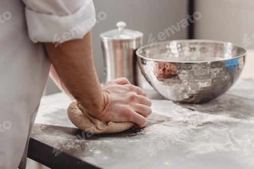 Preview: Baker punchs down the dough in the kitchen in the bakery