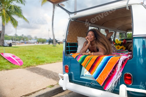 Preview: Beautiful black woman lying in Volkswagen van on the beach in Hawaii