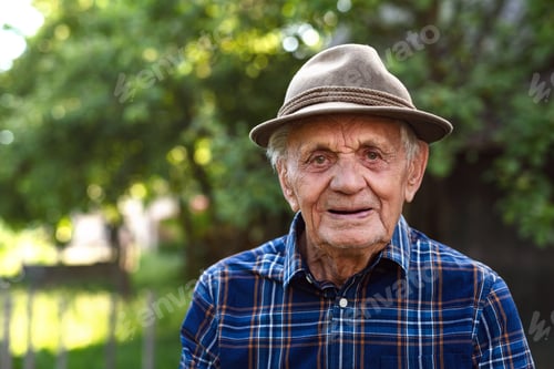 Preview: Portrait of elderly man standing outdoors in garden, looking at camera
