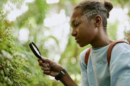 Preview: Black Teenager Looking Closer At Plants In Botanical Garden