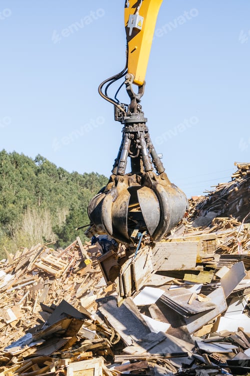 Preview: Crane handling wood waste for recycling in a sunny day