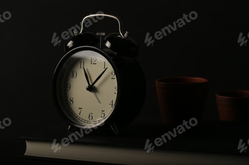 Preview: A Black Book And A Black Watch Stand Against A Black Background