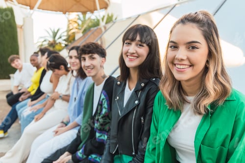 Preview: Happy young ethnic woman sitting with friends on building roof in daylight
