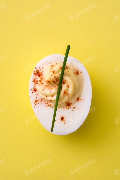 Preview: Deviled egg garnished with paprika and chive on yellow background