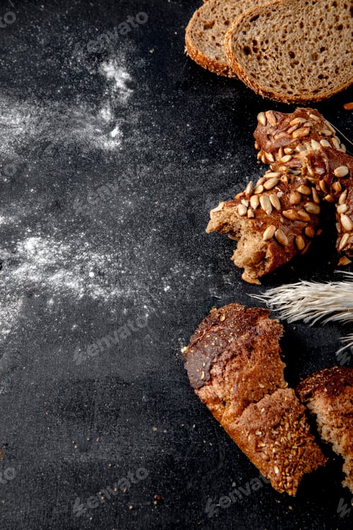 Preview: side view of sliced breads as black bread, bagel and rye on right side and black background with