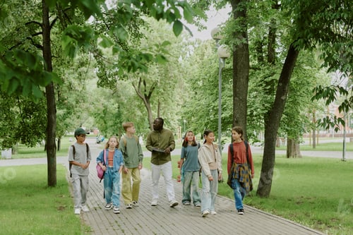 Preview: Multiethnic School Teacher Walking with Group of Children in Park Outdoors