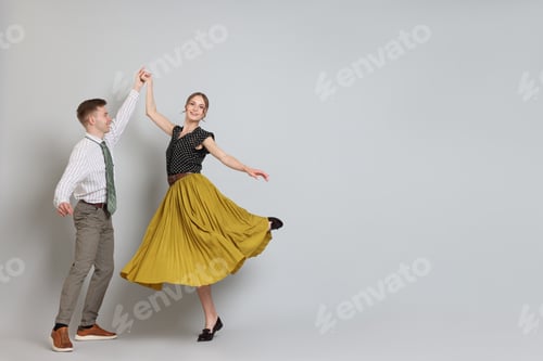 Preview: Happy couple in retro outfits dancing on light grey background, space for text