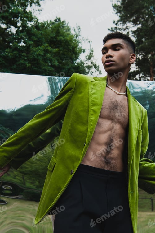 Preview: young african american man in green blazer and beads posing near mirror in park