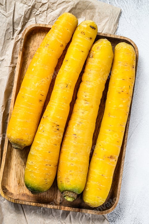 Preview: Fresh Yellow organic carrots without tops in a wooden bowl. Gray background. Top view