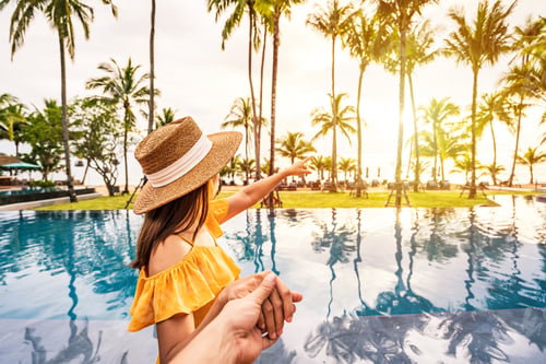 Preview: Young couple traveler relaxing and enjoying the sunset by a tropical resort pool