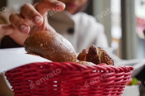 Preview: Hand reaches for bread rolls in a basket at a cafe