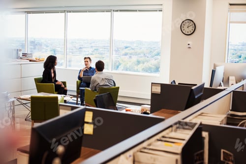 Preview: A woman and two men sitting in armchairs in an office talking to each other.