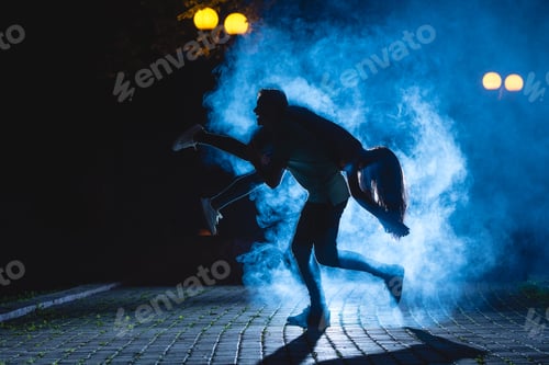 Preview: The man hold a woman on the dark street with a blue fume. night time