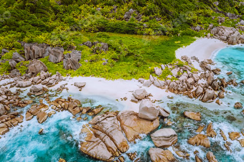 Preview: Aerial top view of ocean waves hitting granite rocks on the Anse Marron beach, La Digue, Seychelles