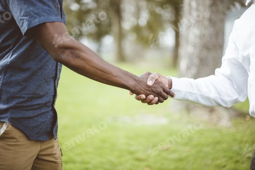 Preview: Closeup shot of two males shaking hand with a blurred background -