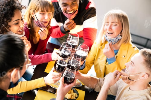 Preview: Happy friends wearing protective face masks toasting red wine sitting at bar restaurant
