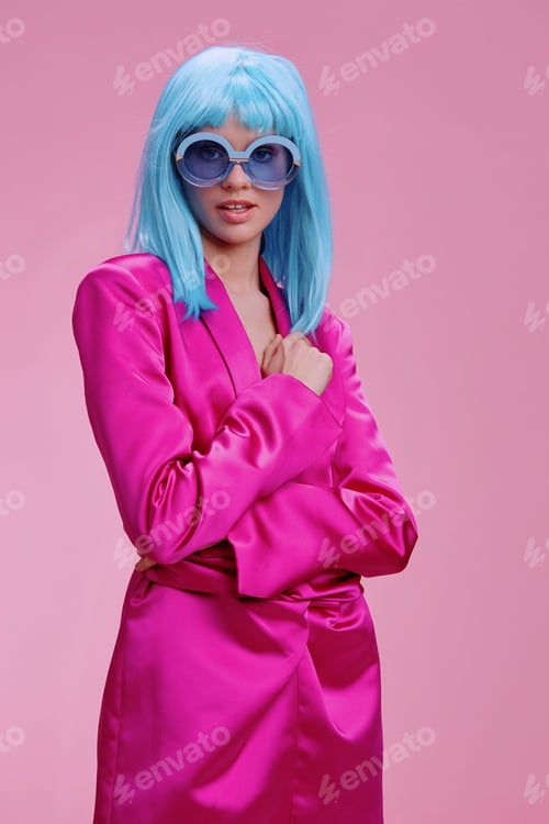 Preview: Pink suit, blue wig, sunglasses a woman in a bright pink suit with a blue wig poses confidently with