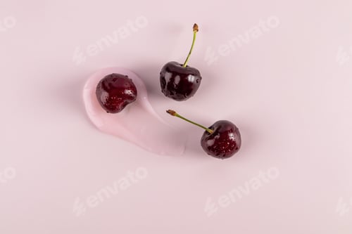 Preview: Beautiful brushstroke of cosmetic texture of balm, mask, lip gloss with ripe cherries. top view