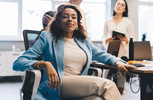 Preview: Positive black woman resting on chair during break from work