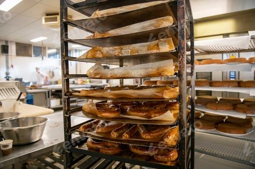 Preview: Freshly baked bread on metal racks in a commercial kitchen with a chef working in the background.