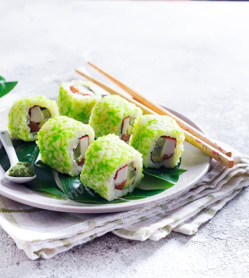 Preview: sushi roll with green caviar on a plate with chopsticks on stone background . Sushi menu. Japanese
