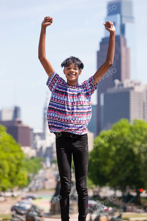 Preview: Portrait of young man with arms raised in front of city skyline, Philadelphia, Pennsylvania, USA