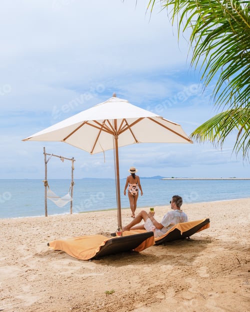 Preview: Men and women on a sunny day relaxing in beach chair with a hammock on the beach in Pattaya Thailand