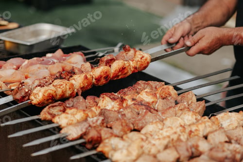 Preview: Frying shish kebab on the skewers in brazier. Fresh ruddy meat for barbecue grill on fire outdoor.