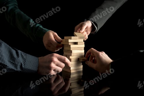 Preview: View of four male hands pulling pieces from tower