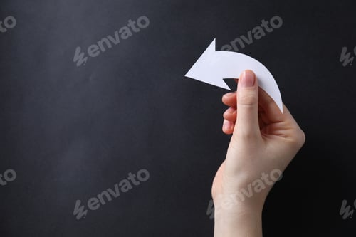 Preview: Woman with paper arrow on black background, top view. Space for text
