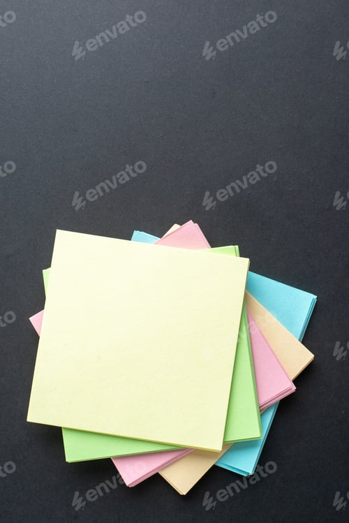 Preview: Above view of stacked sticky coloured note cubes on the bottom on isolated black wave background