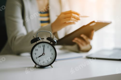 Preview: Alarm clock on the desk. Business hand using smartphone, laptop and tablet working in modern office